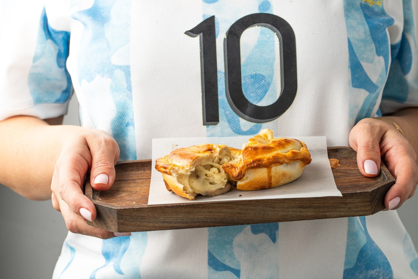 Empanadas served on a wooden board with an Argentina number 10 jersey