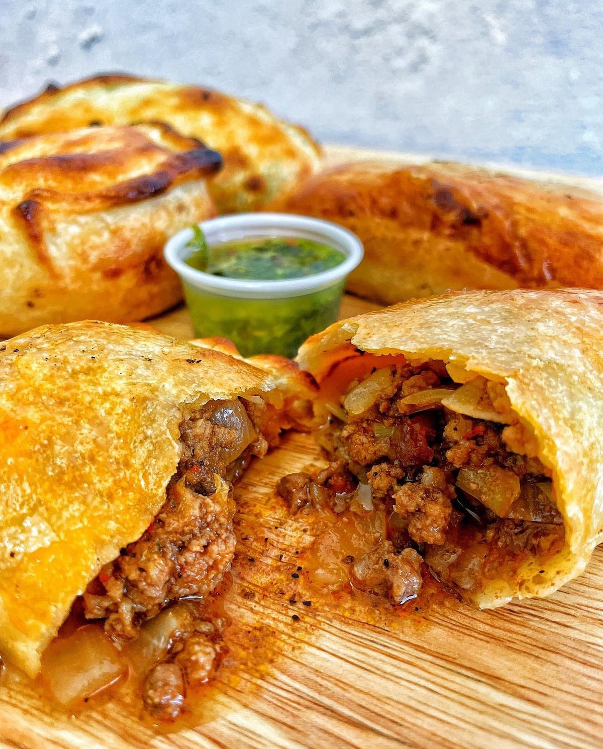Beef empanadas served on a board with chimichurri